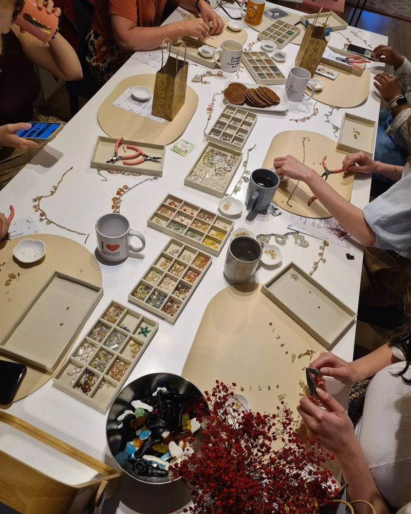 Deelnemers ontwerpen persoonlijke sieraden tijdens een workshop op locatie.
